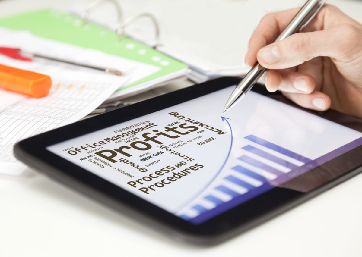 Hand holding pen over a PC tablet screen. On the screen there is an arrow pointing upward.