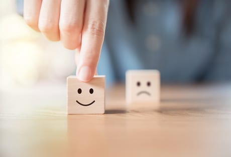 Wooden blocks on a table with a smiley & frowney face, Customer Experience Coordinator: Promoting Company Confidence