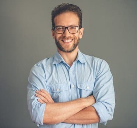 Bearded man wearing glasses & a blue button up shirt.