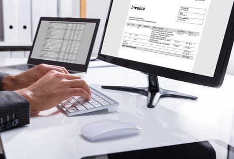 Office desk with laptop, keyboard, mouse, & display