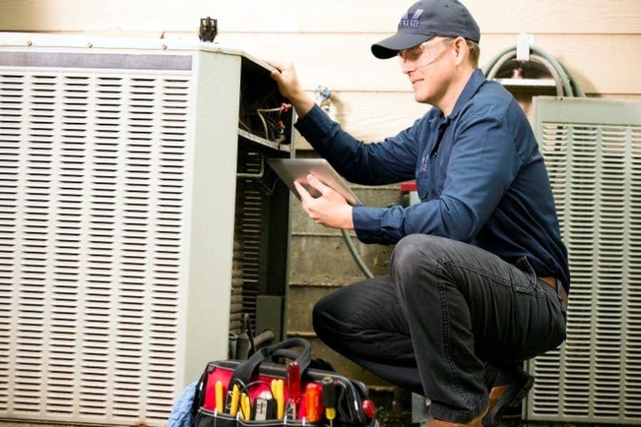 HVAC service technician working on outdoor air conditioner unit.